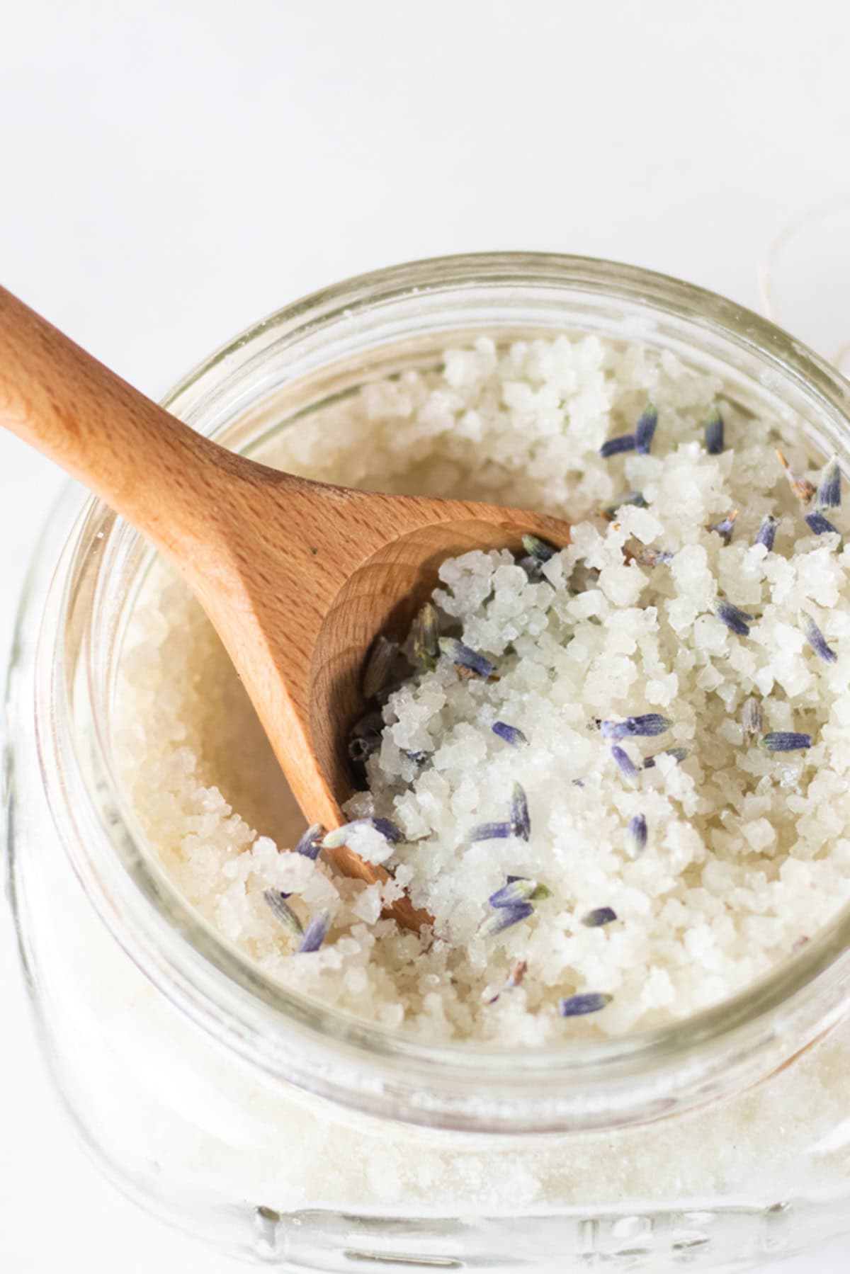 A jar of detoxifying foot bath with a wooden spoon sticking out of it.