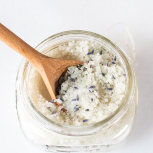 A jar of detoxifying foot bath with a wooden spoon sticking out of it.