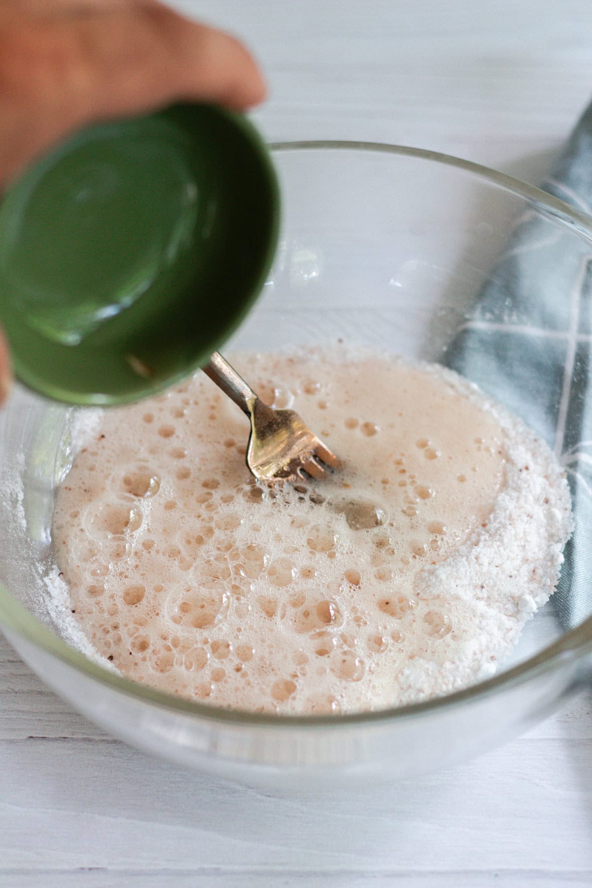 Adding apple cider vinegar to the bowl of ingredients and stirring it with a fork.
