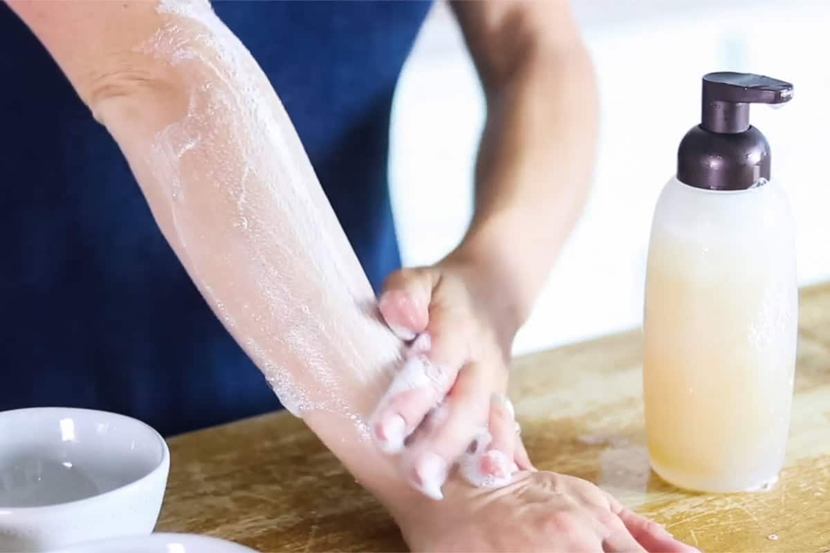 Using homemade natural body wash on the arm with a bottle of the body wash to the side.