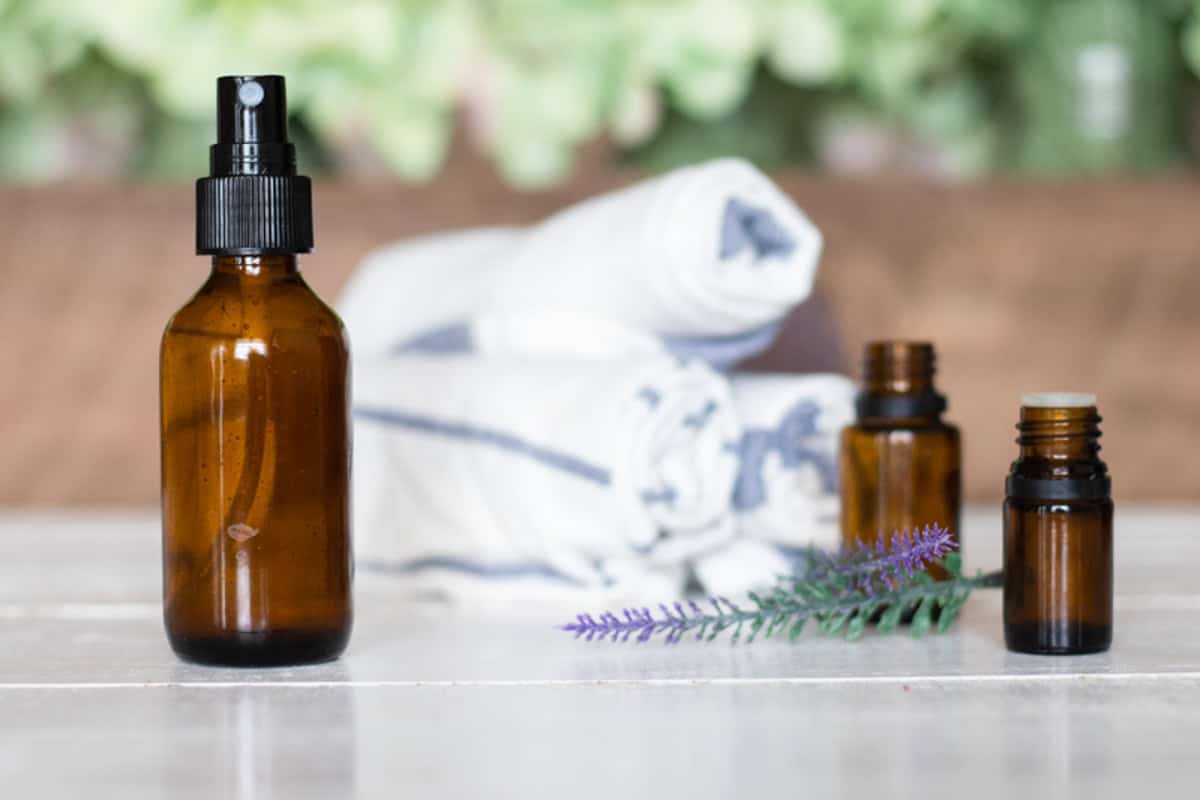 An amber spray bottle of spray deodorant with essential oils and towels and in the background.