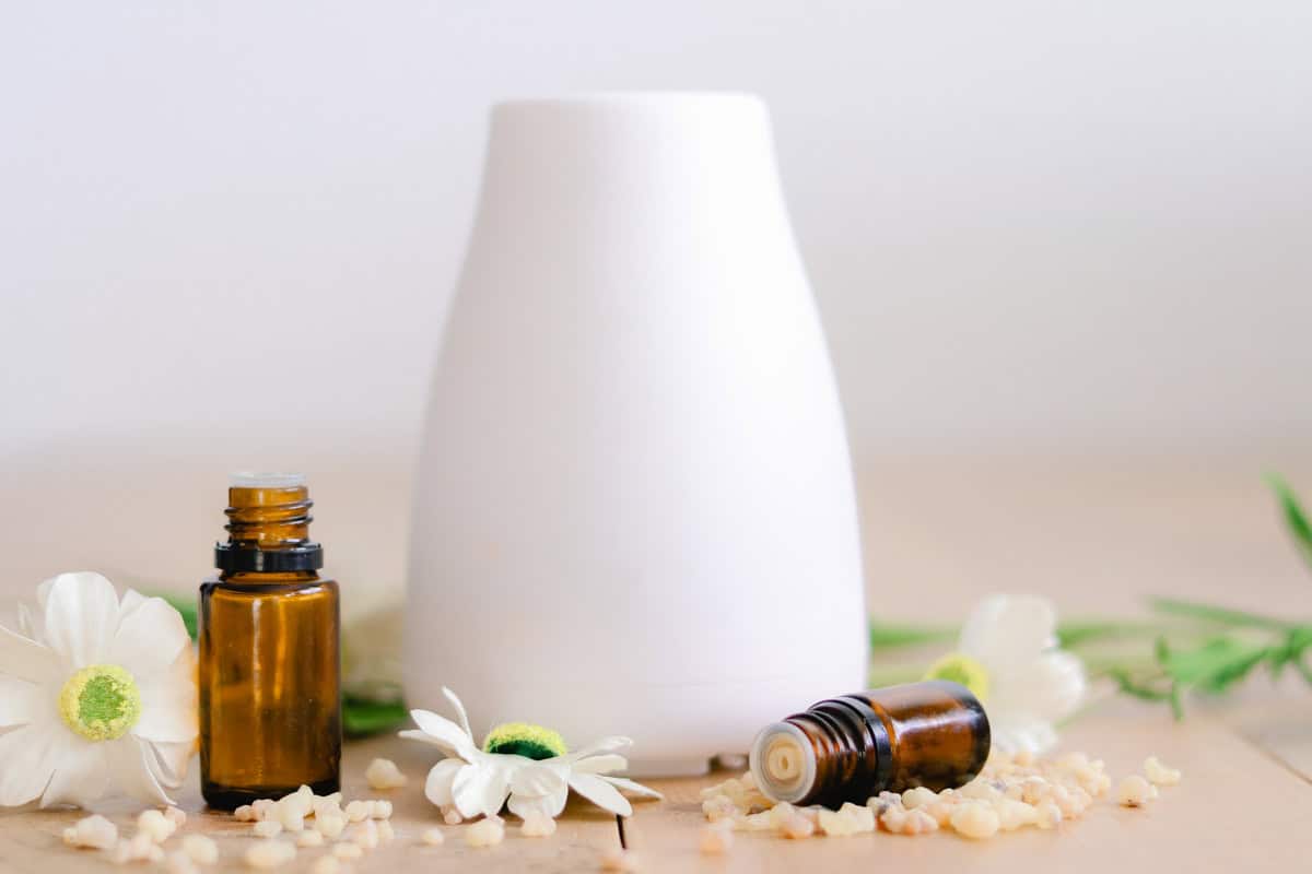 Tall diffuser with essential oil bottles for mood support next to it on a wooden table. 