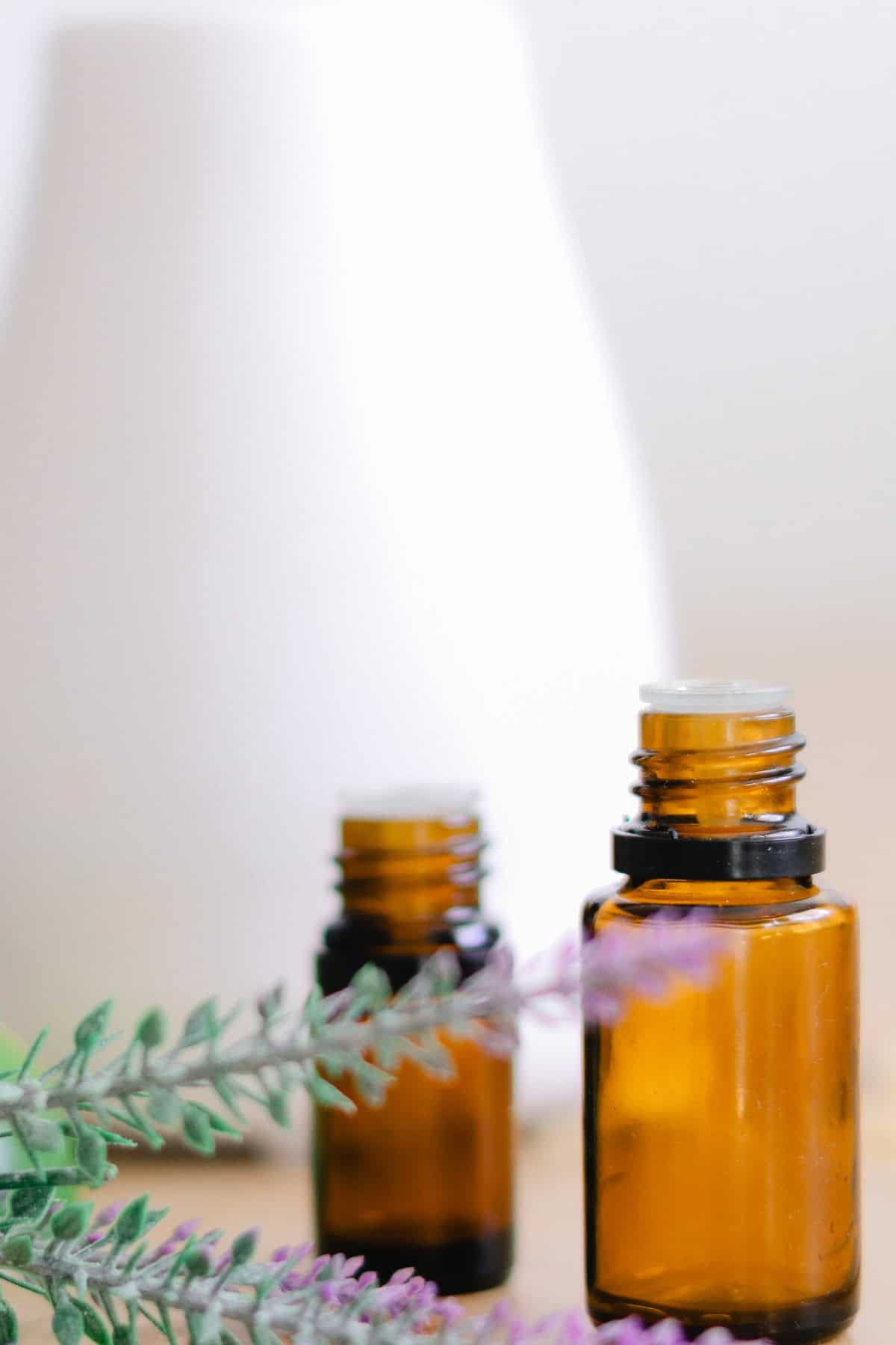 Essential oil diffuser with oil bottles and dried lavender sprigs next to it. 