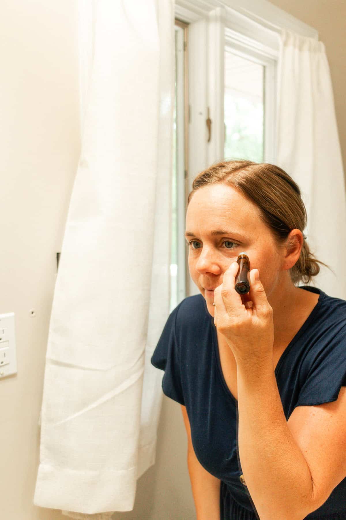 Applying an essential oil roller bottle under the eyes.