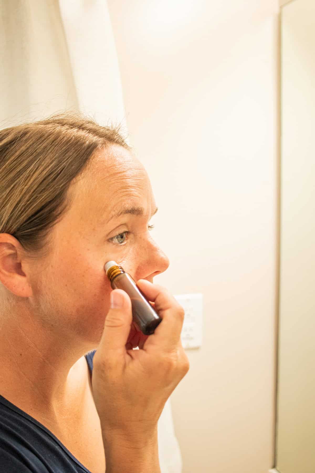 Applying a roller bottle to the under eyes.