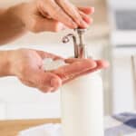 Pumping homemade goat milk lotion into the palm of a hand.