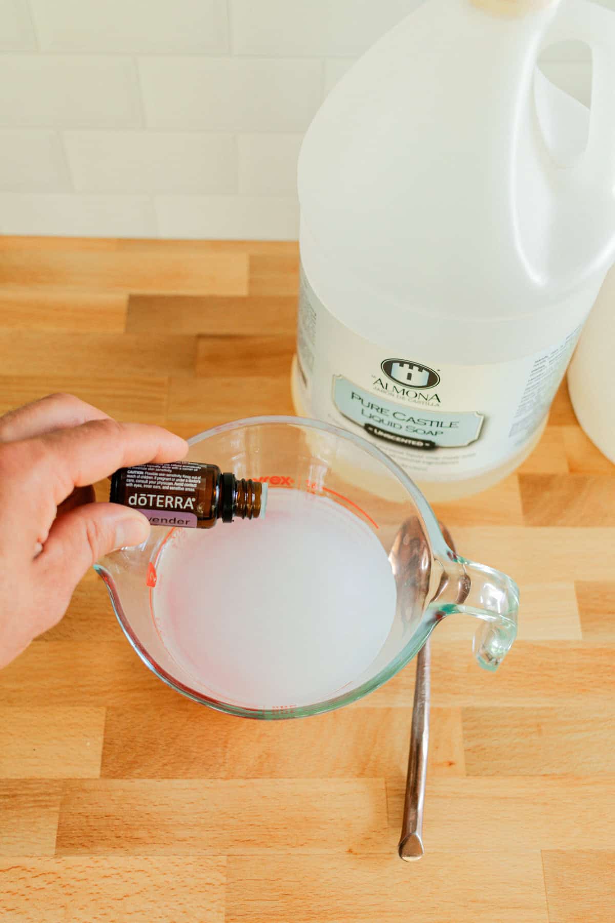 Adding essential oils to a bowl of baby wipe solution.