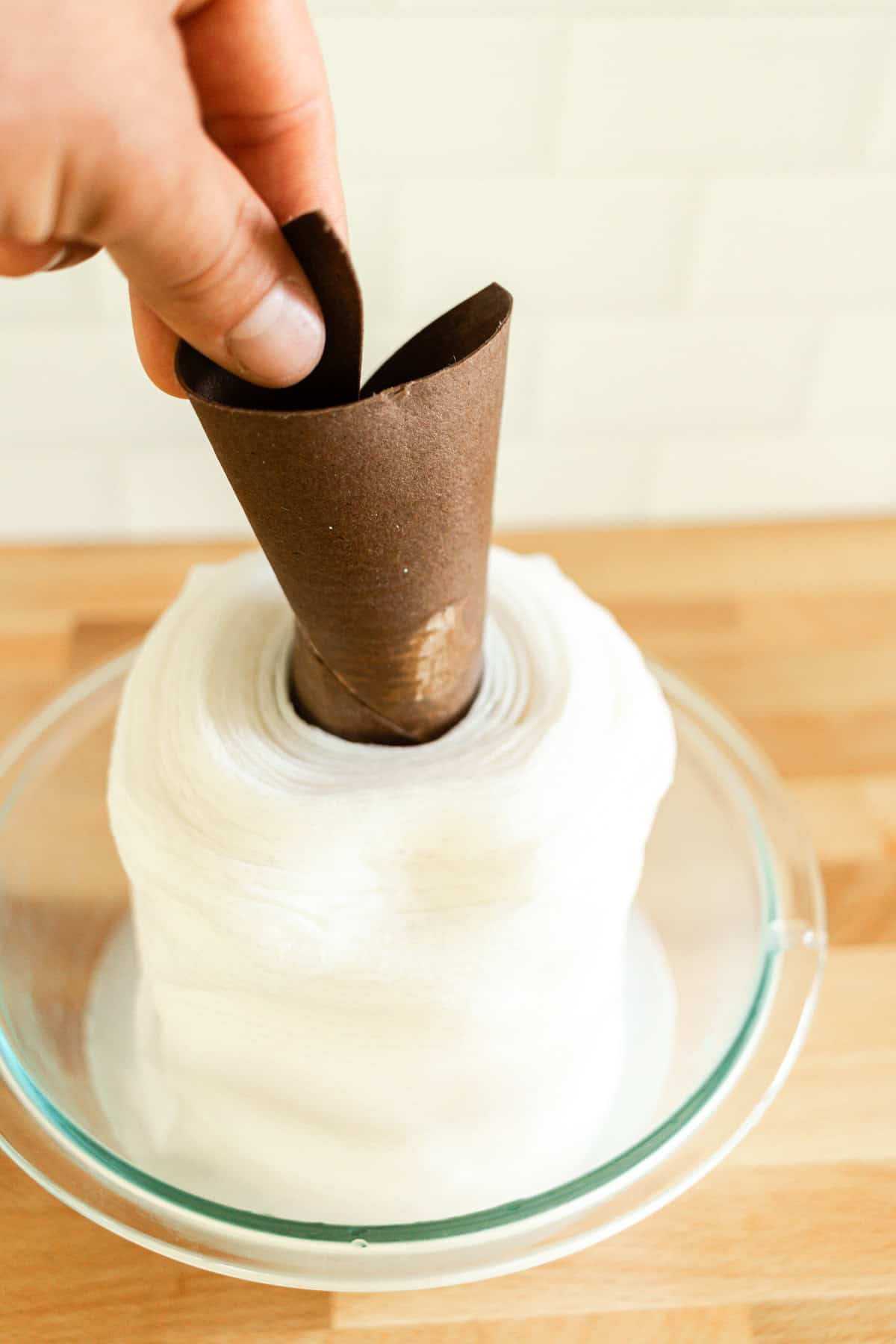 Pulling a soaked paper towel roll out of the center of a roll of paper towels.