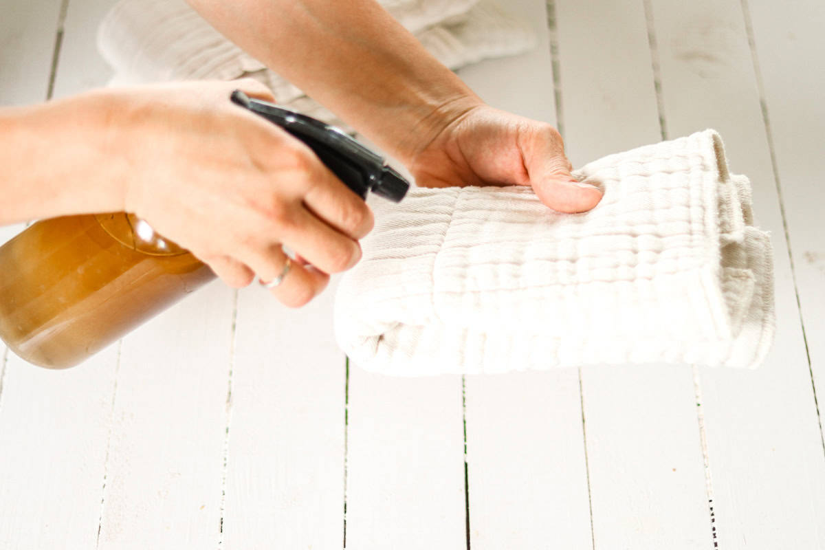 Spraying a wipe with baby wipe solution in a spray bottle.