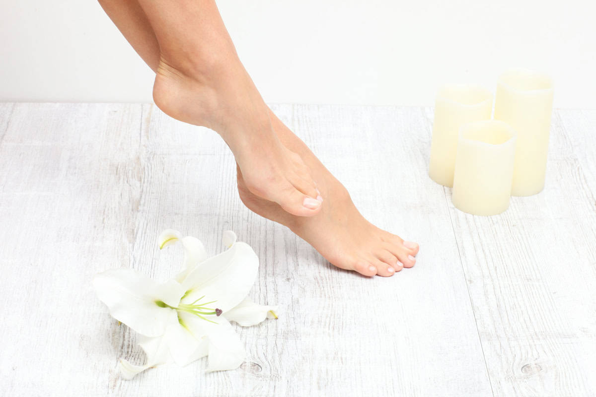 A photo of feet with candles next to them.