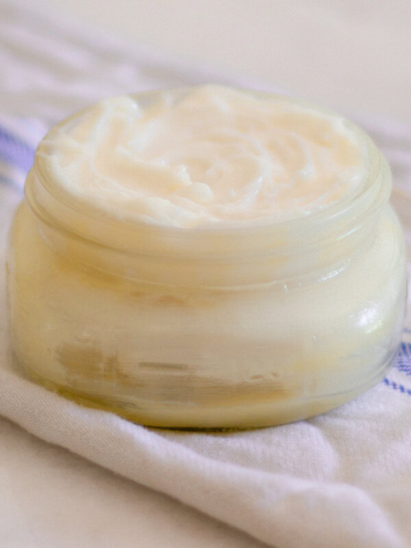 A jar of whipped mango body butter on a white and blue towel.