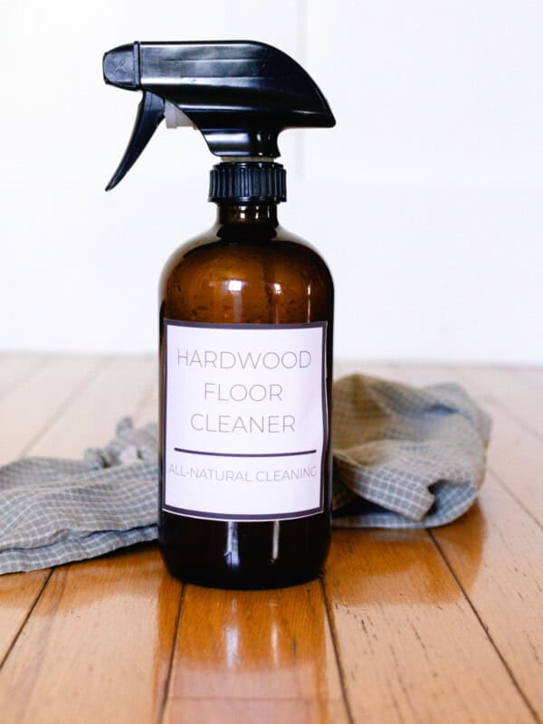 A spray bottle of homemade wood floor cleaner with a cloth rag.