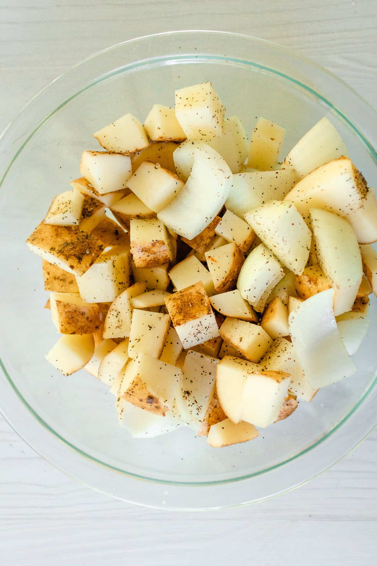 Dice the potatoes and onions and toss them in a small bowl with avocado oil, salt, and pepper.