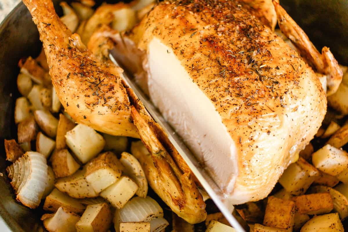 Cast iron roasted chicken with red potatoes with a slice.