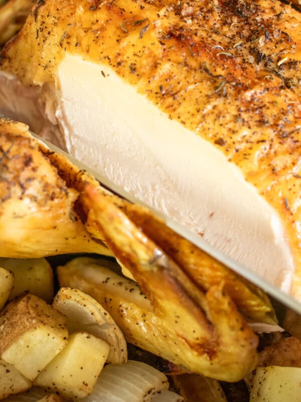 Carving roasted whole chicken in cast iron skillet.