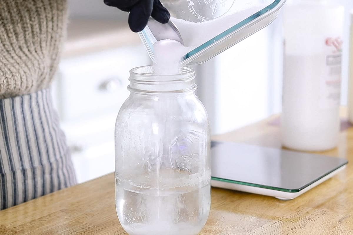 Pouring lye into a jar of water.