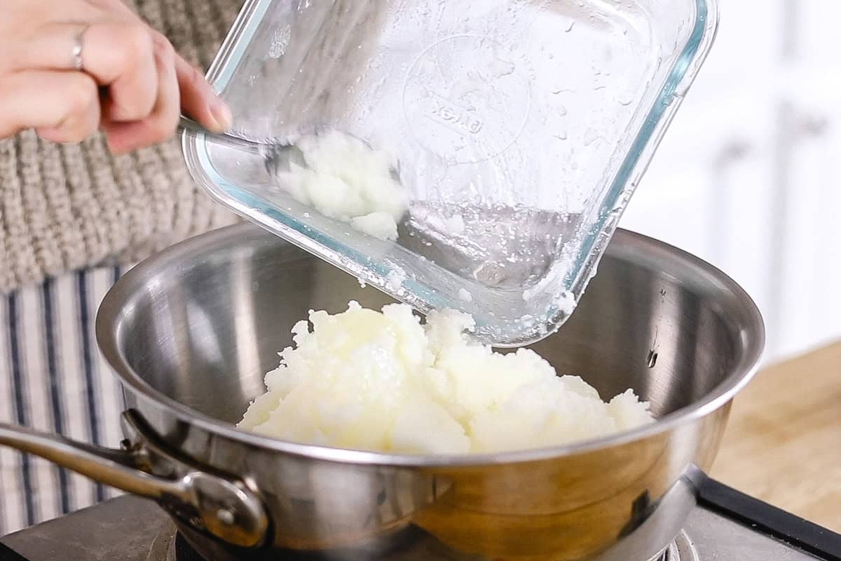 Scooping coconut oil into a metal bowl.