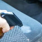 Spraying DIY car seat cleaner on a car seat.