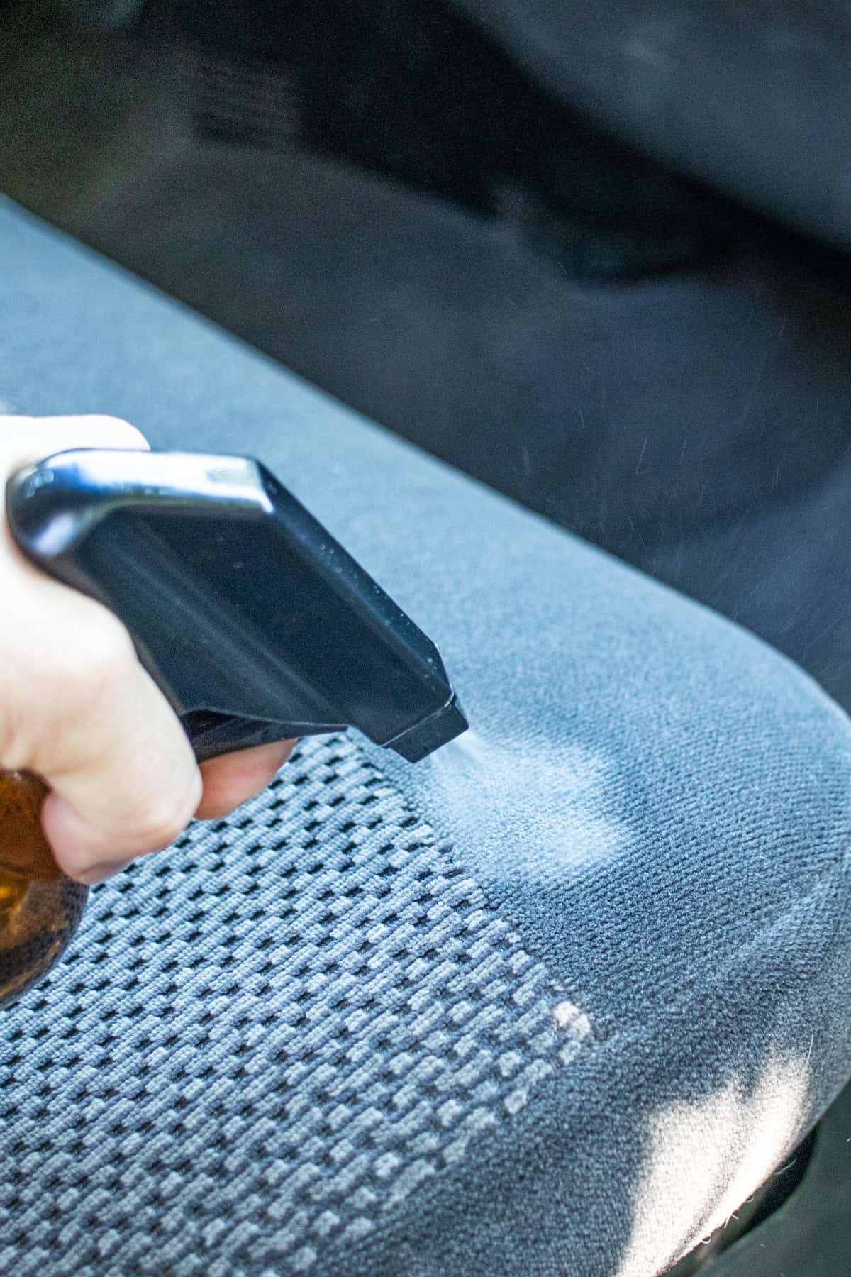 Spraying DIY car seat cleaner on a car seat.