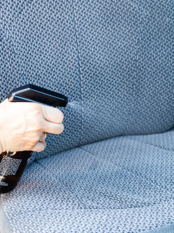 Spraying cleaner on a car seat.