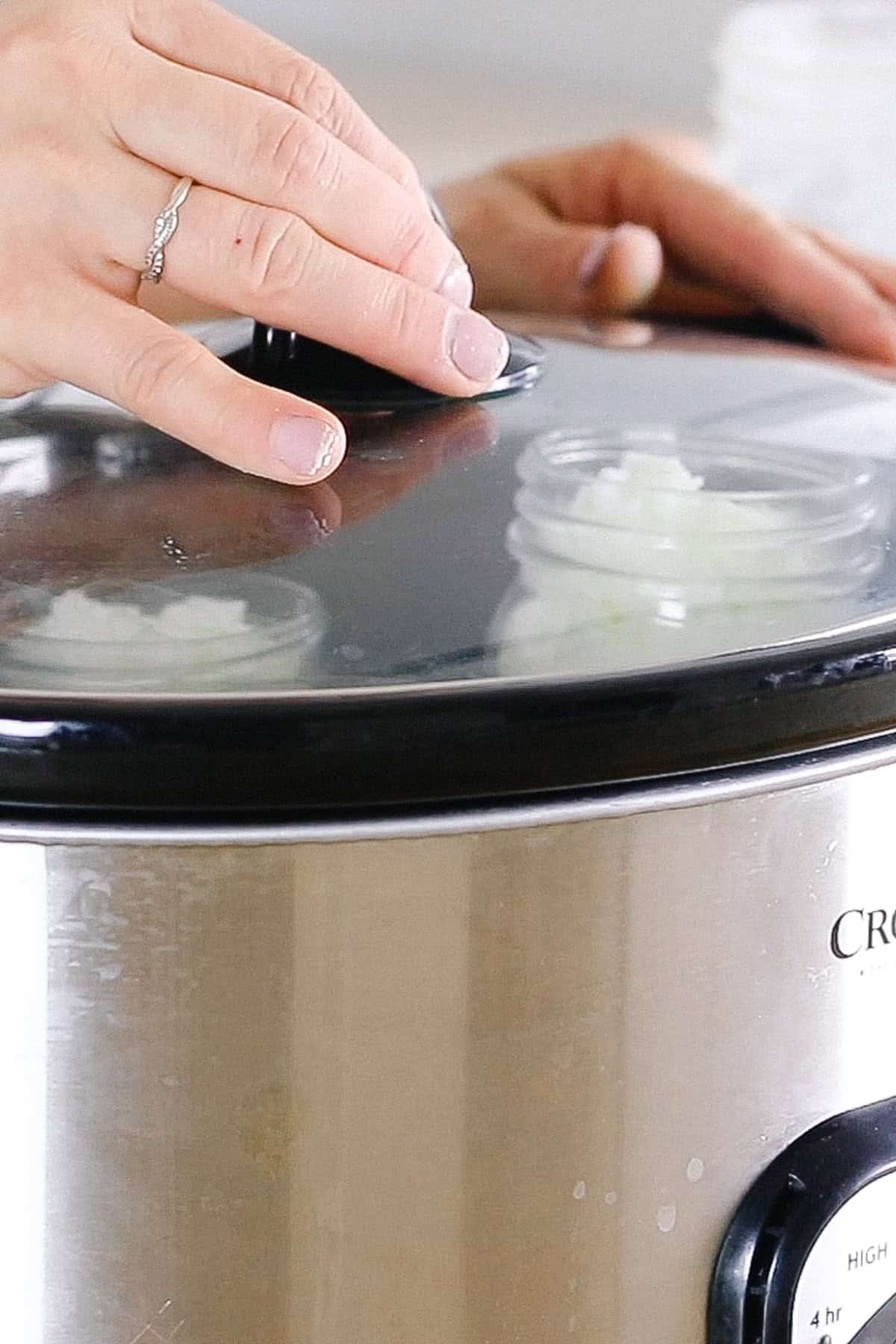 Placing a lid on a crockpot with candles inside.