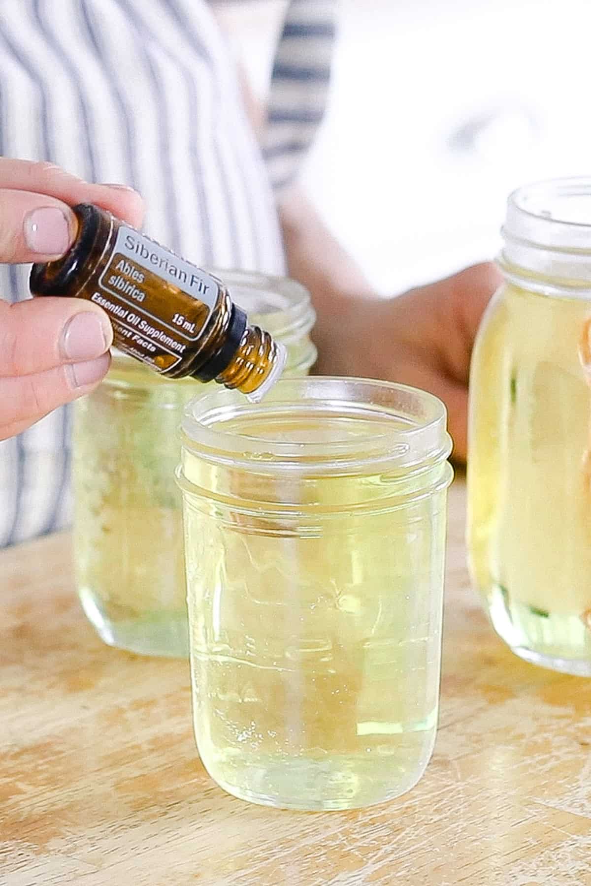 Adding essential oils to a jar of melted wax.