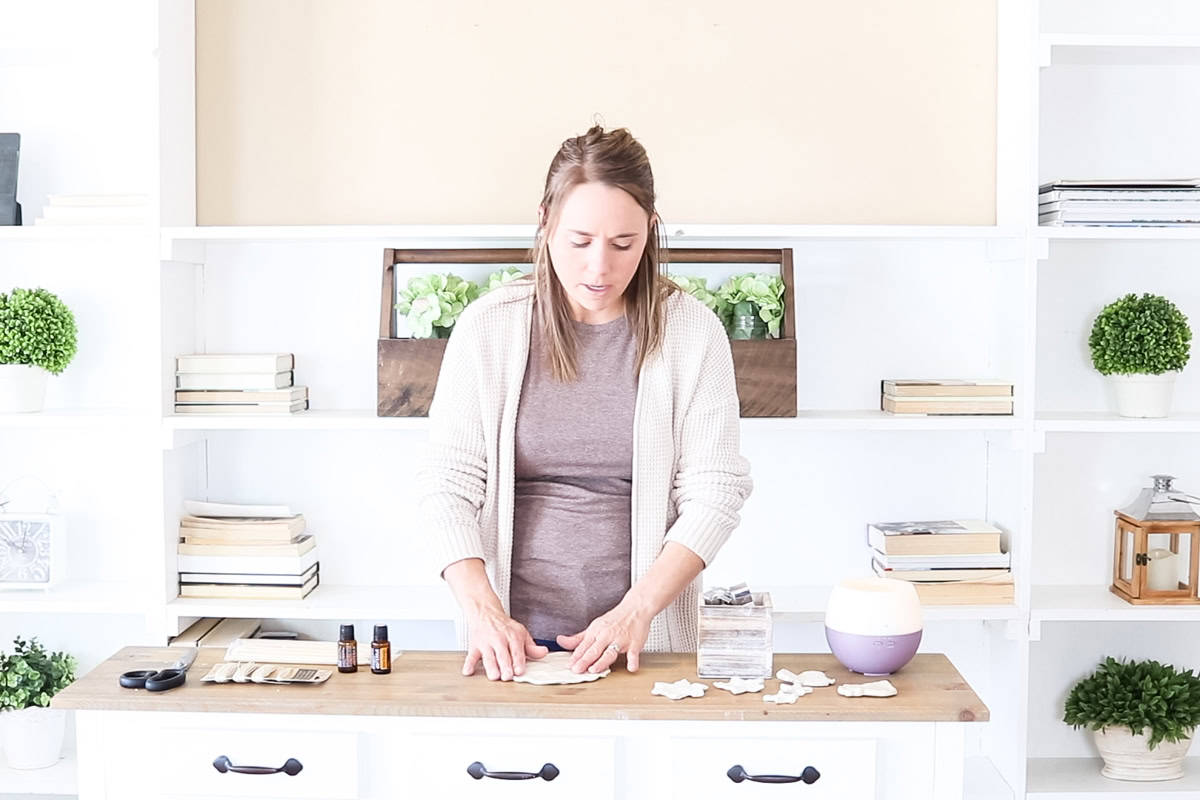 Standing at a counter pressing a ball of clay into a patty.