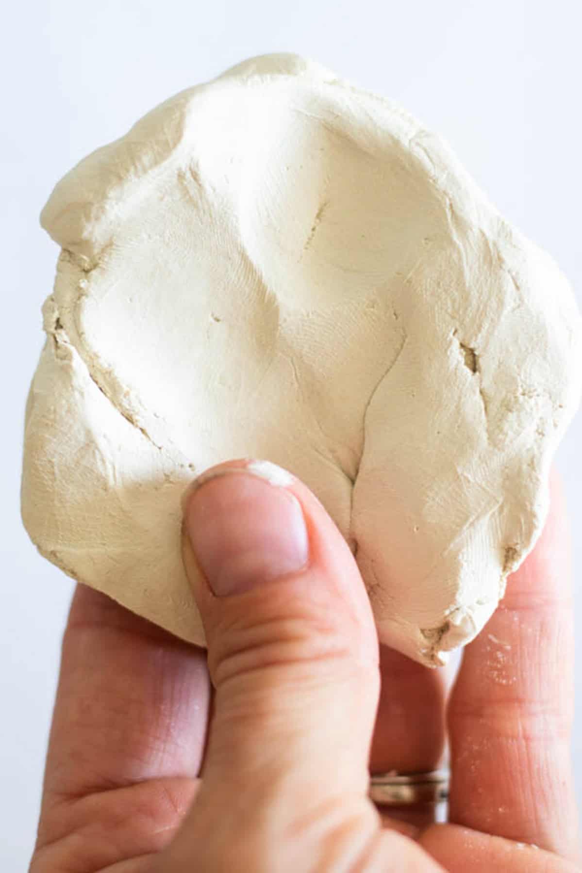 Shaping a piece of clay into a flat, circular shape.