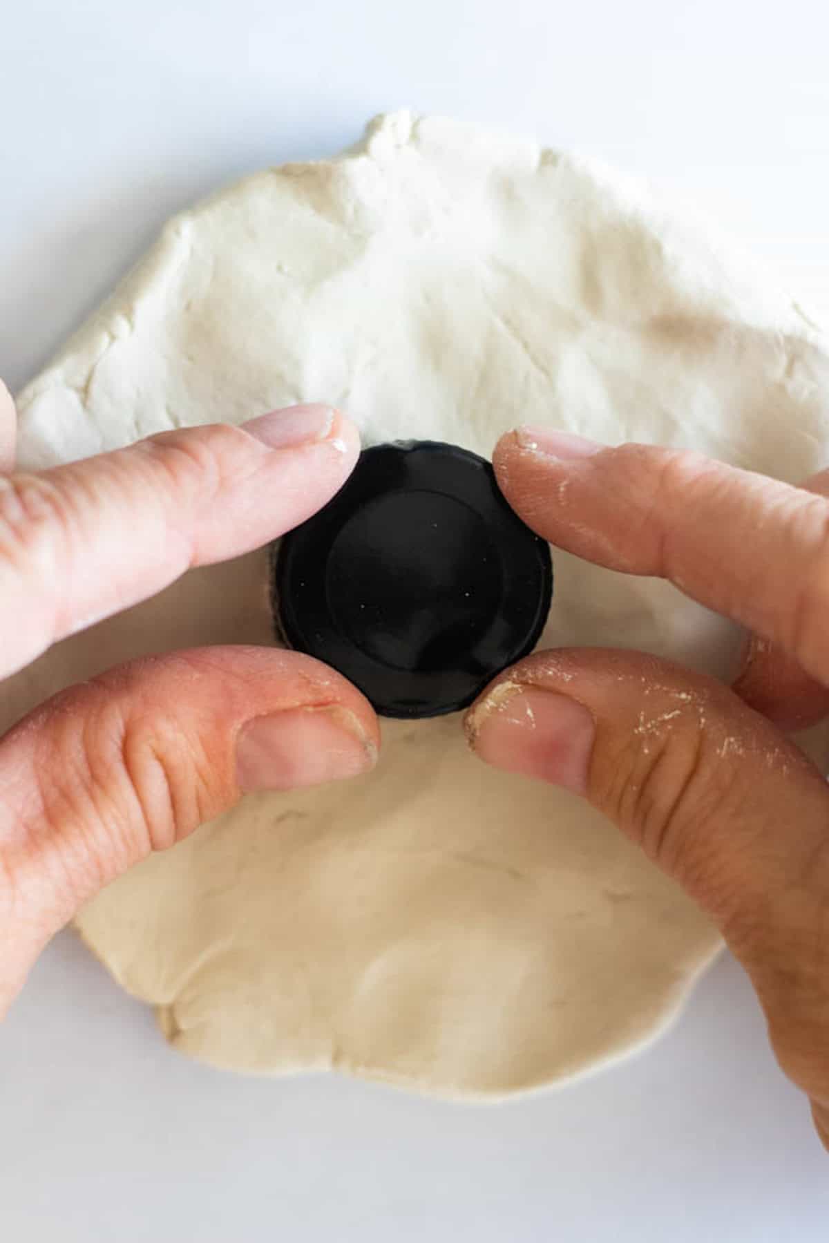 Pressing a circular cap into a sheet of clay.