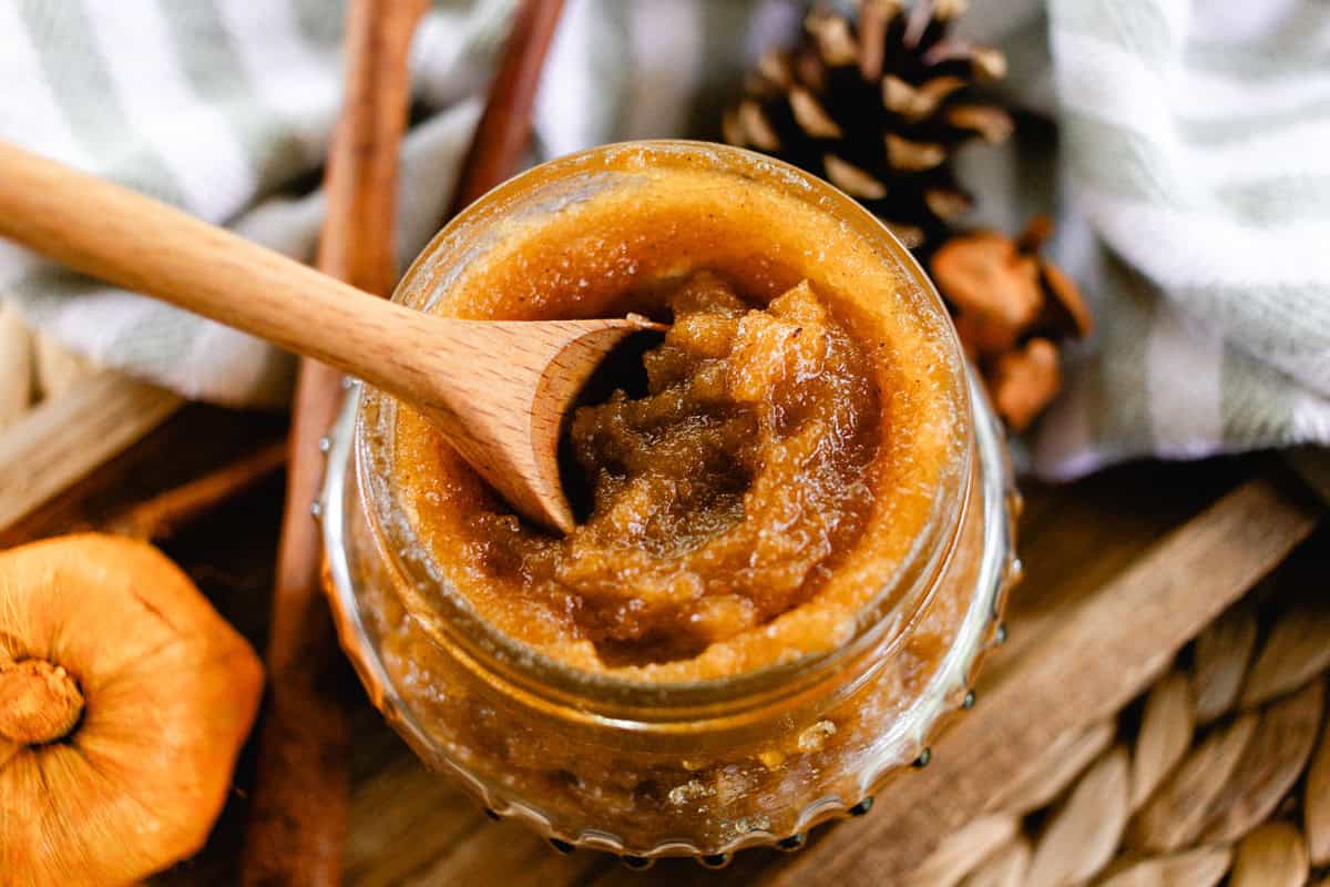 A jar of fall body scrub with a wooden spoon in it.