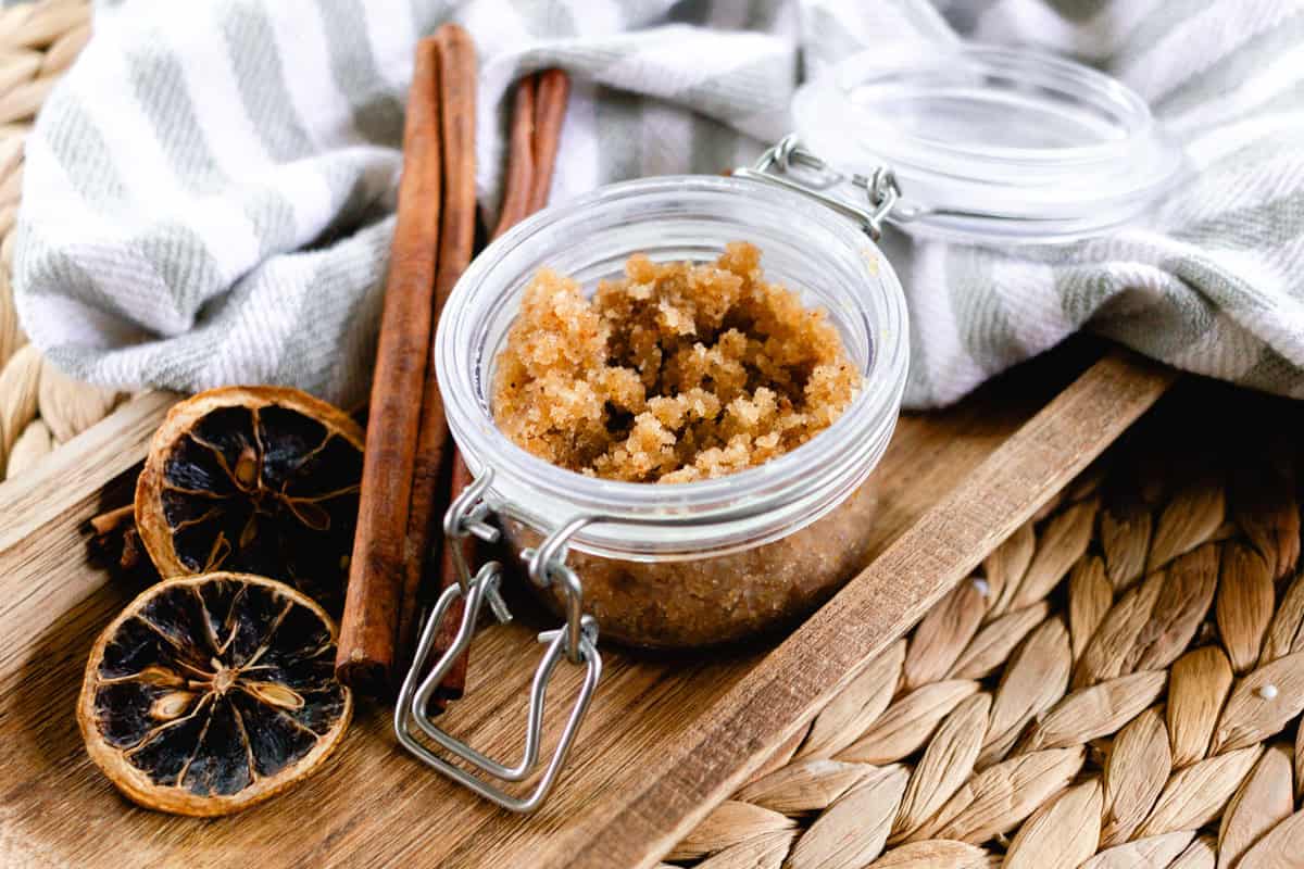 A jar of gingerbread body scrub with dried oranges and cinnamon sticks.