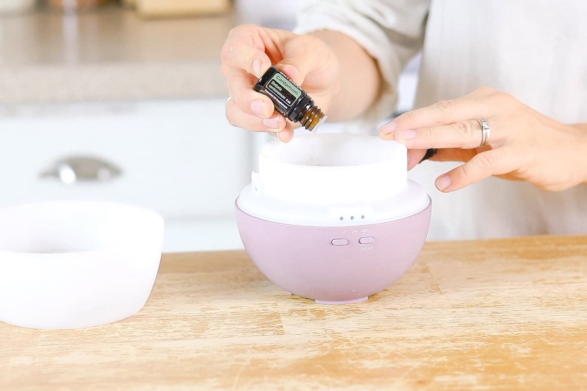 Dropping essential oil into a purple diffuser.