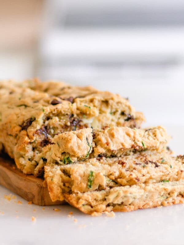 A loaf of gluten-free zucchini bread sliced on a cutting board.