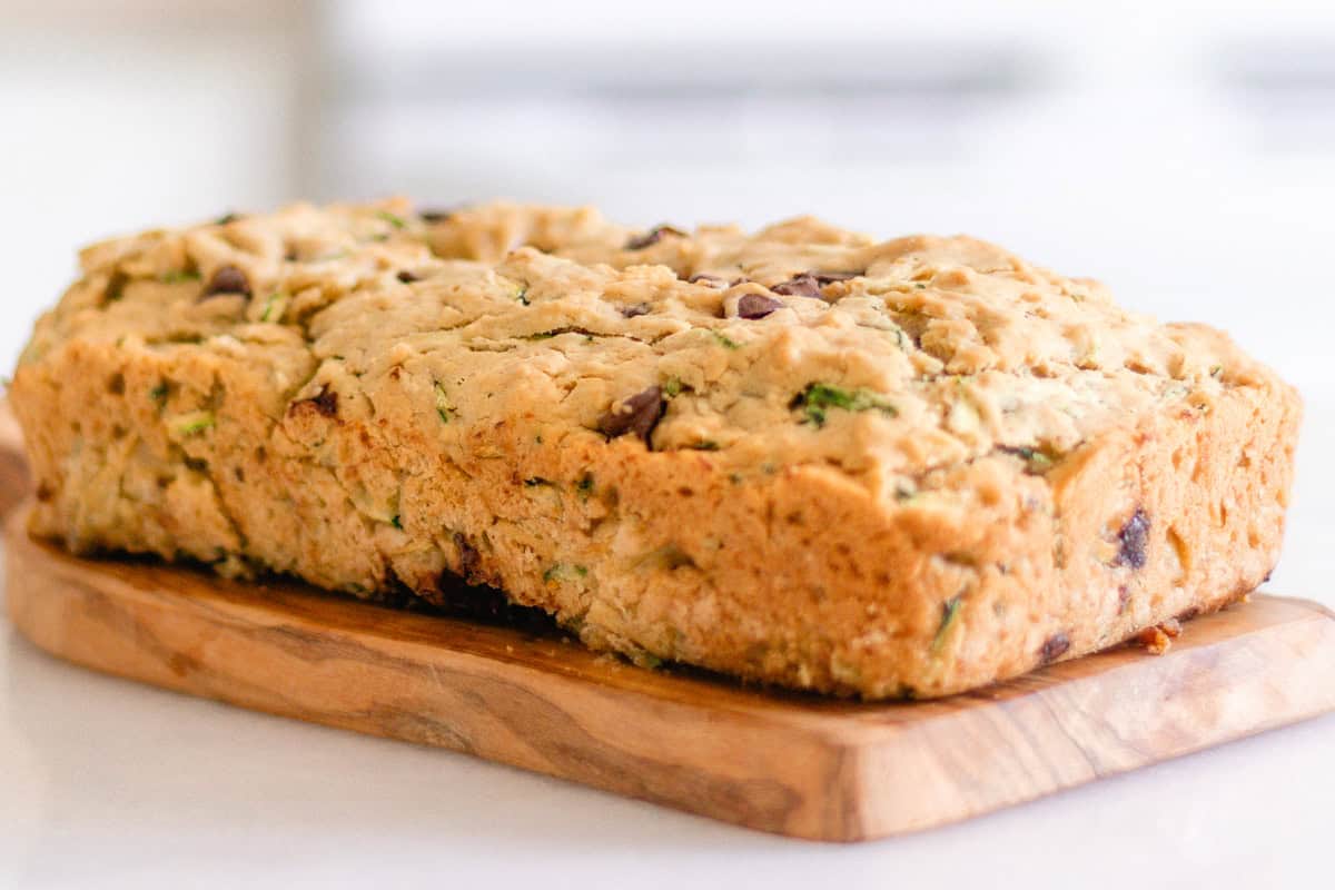 A loaf of gluten-free zucchini bread on a wooden board.
