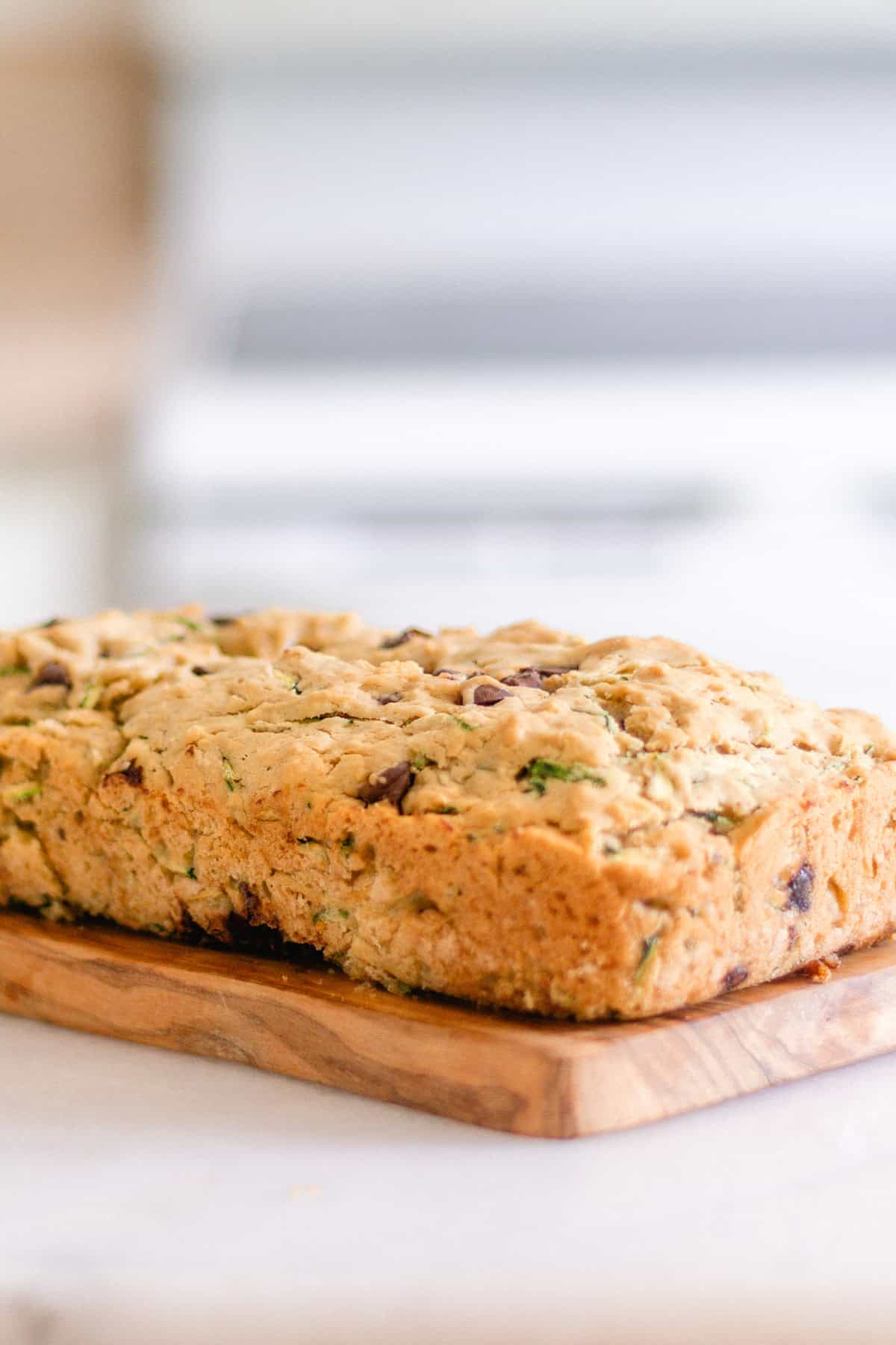 A loaf of gluten-free zucchini bread on a wooden board.