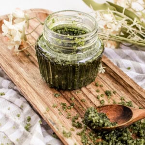 Green tea matcha scrub in a jar on a wooden board with a spoon.