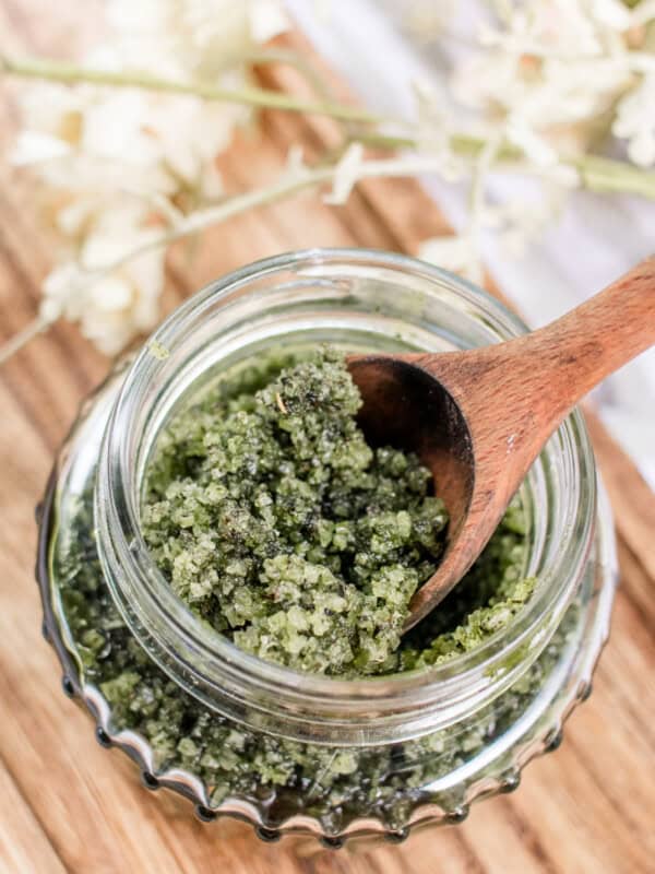 Green tea matcha scrub in a jar with a spoon sticking out of it.