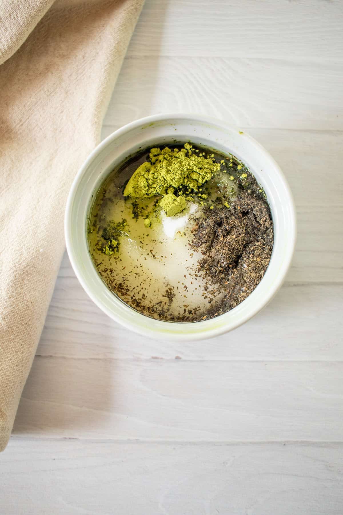 Matcha scrub ingredients in a bowl with liquid.