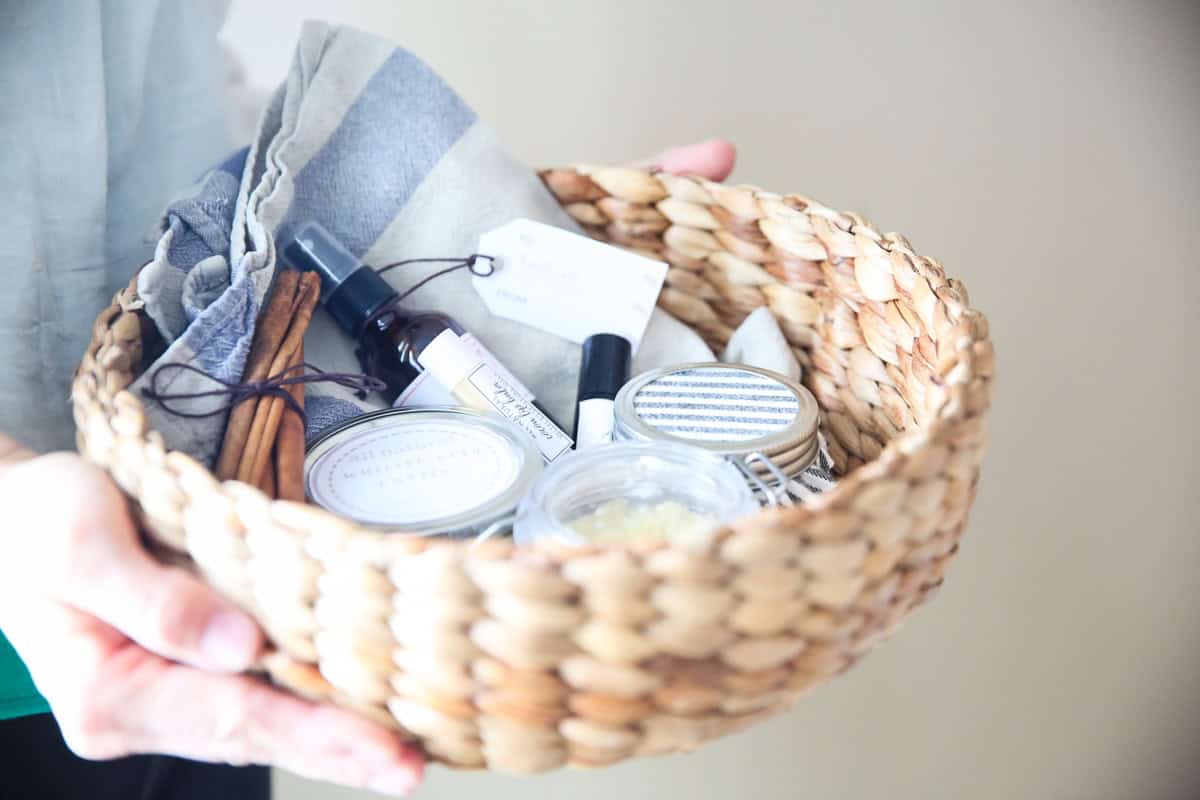 Holding a gift basket filled with bath and beauty products.