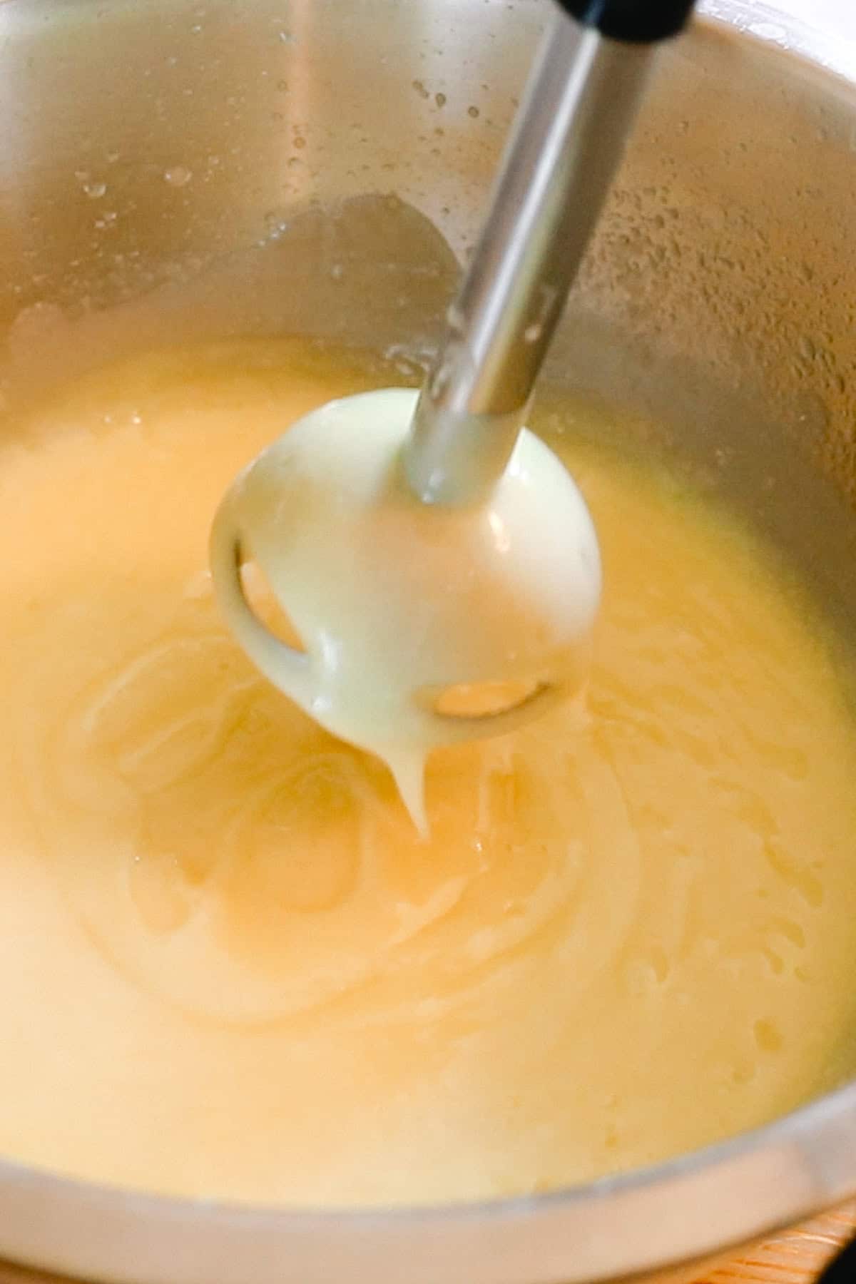 Checking the trace of the soap mixture by holding the immersion blender over it as the soap drips down.