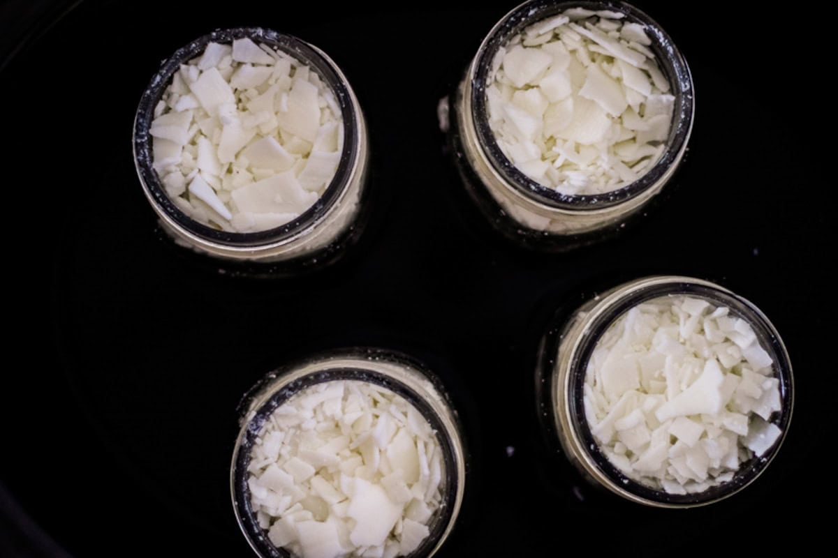 Jars of wax pellets in a crockpot, looking down.