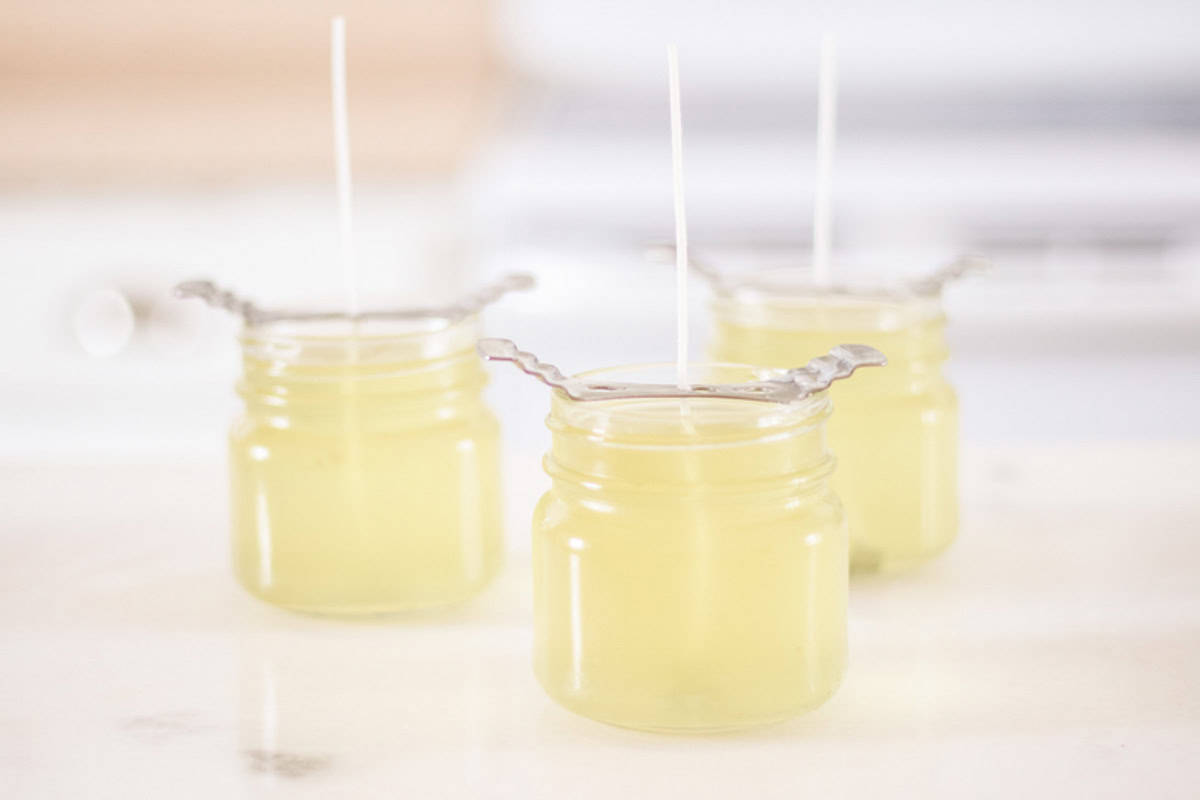 Candles with wick holders cooling on a countertop.