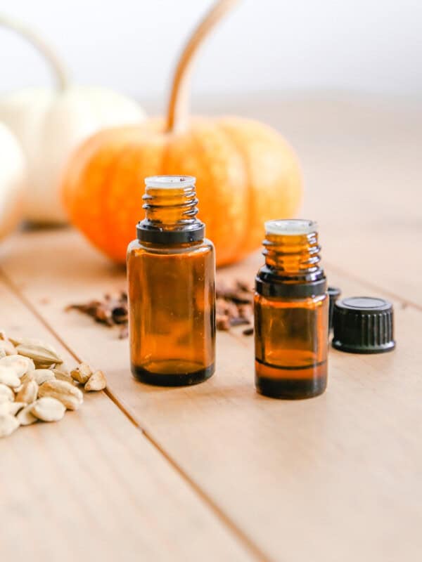 Two bottles of essential oils with pumpkins in the background.