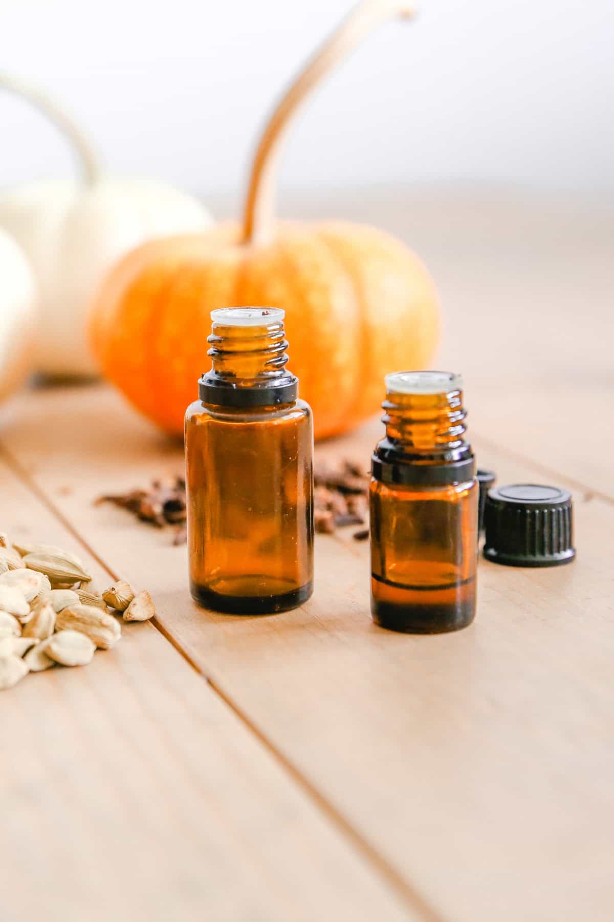 Two bottles of essential oils with pumpkins in the background.