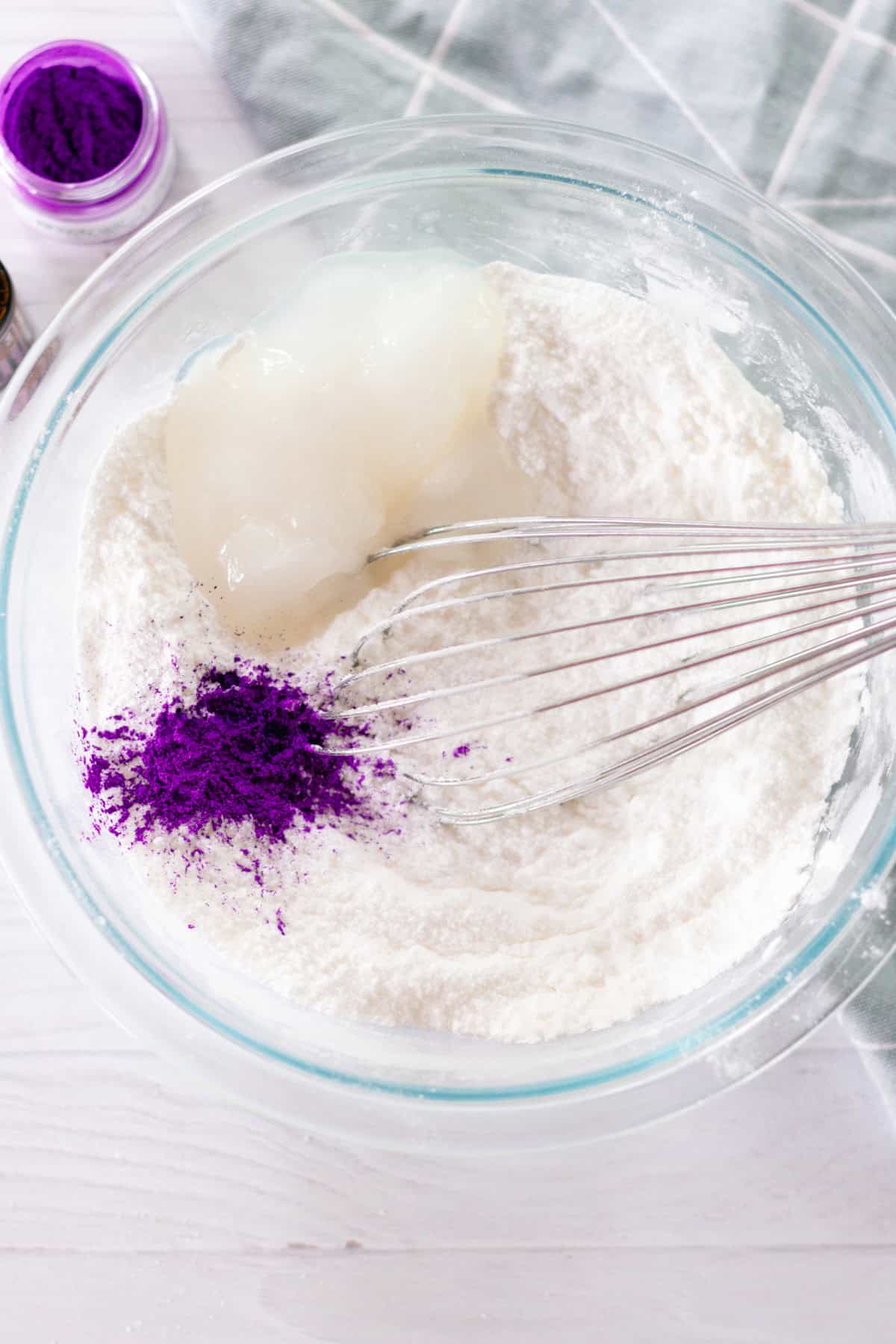 Bath bomb ingredients in a glass bowl with a whisk.