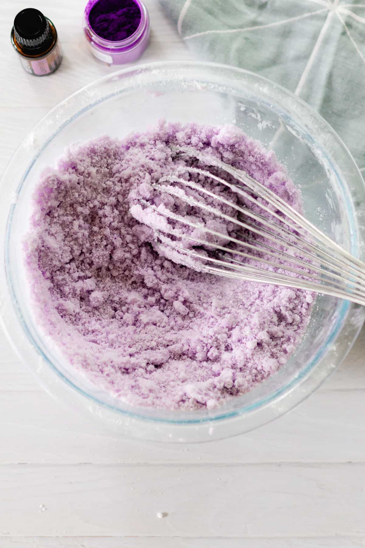 Mixing the ingredients with a whisk on a white wooden table. 