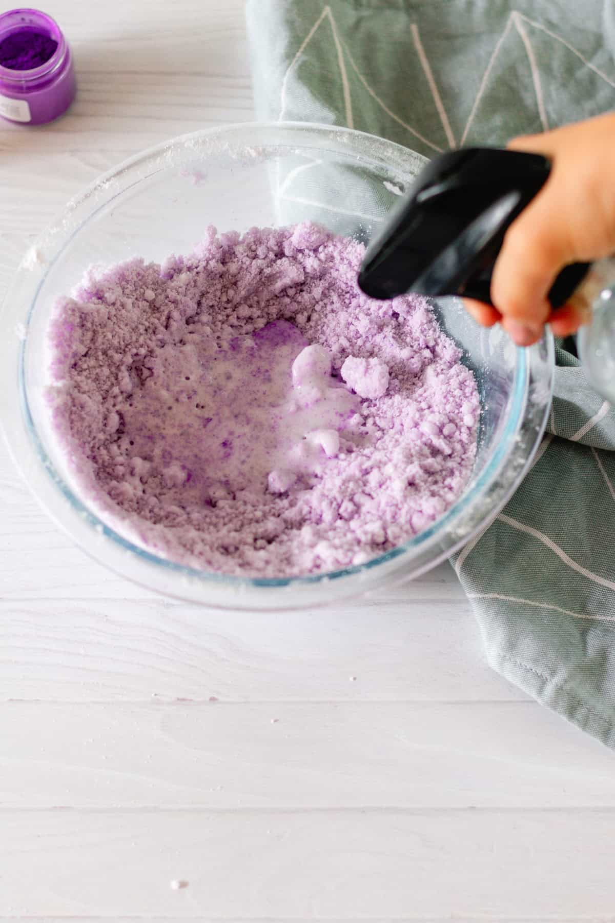 Misting water into the mixture to get the right texture of the bath bombs.