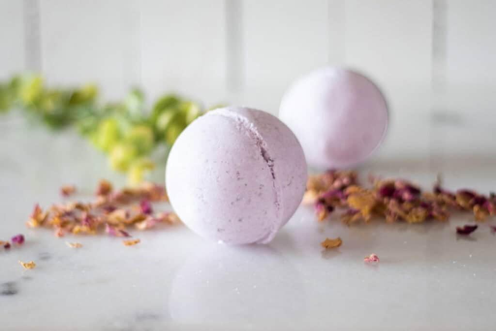 Two bath bombs on a counter with dried flowers.
