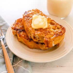 A white plate with a stack of sourdough french toast on a blue napkin.
