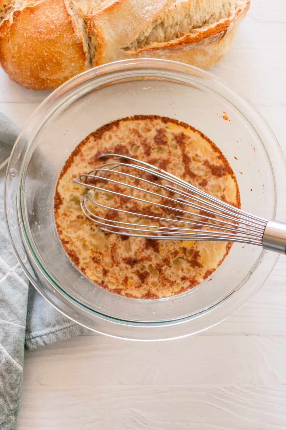 Mixing egg mixture for french toast in a glass bowl.
